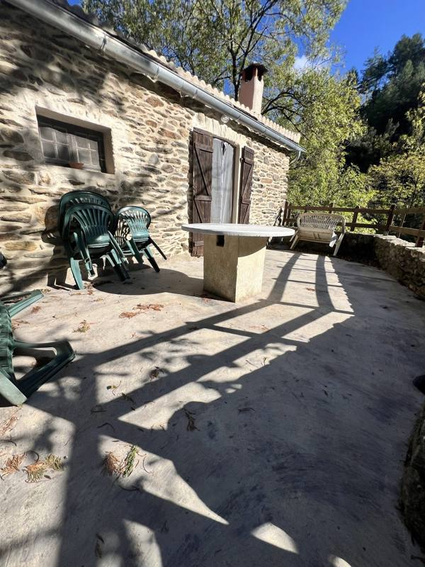 Façade en pierre de Moulin 2 et sa terrasse avec table et chaises de jardin